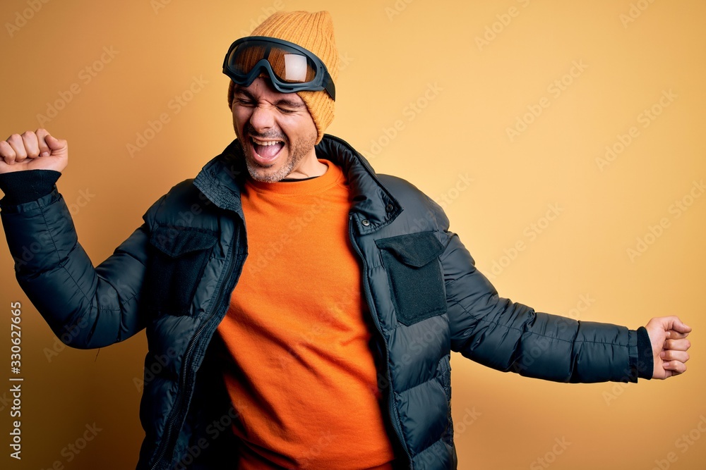 Young handsome skier man skiing wearing snow sportswear using ski goggles Dancing happy and cheerful, smiling moving casual and confident listening to music Young handsome skier man skiing wearing snow sportswear using ski goggles Dancing happy and cheerful, smiling moving casual and confident listening to music