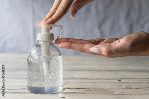 Young woman using hand sanitizer gel with liquid alcohol disinfectant for prevention of coronavirus and other pandemic and epidemic diseases photo