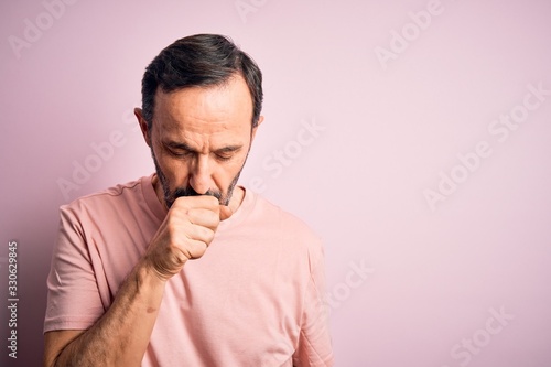 Middle age hoary man wearing casual t-shirt standing over isolated pink background feeling unwell and coughing as symptom for cold or bronchitis. Health care concept.