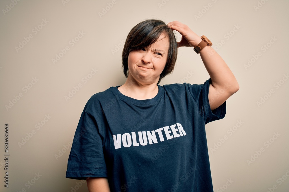 Young down syndrome volunteer woman wearing social care charity t-shirt confuse and wondering about question. Uncertain with doubt, thinking with hand on head. Pensive concept. Young down syndrome volunteer woman wearing social care charity t-shirt confuse and wondering about question. Uncertain with doubt, thinking with hand on head. Pensive concept.