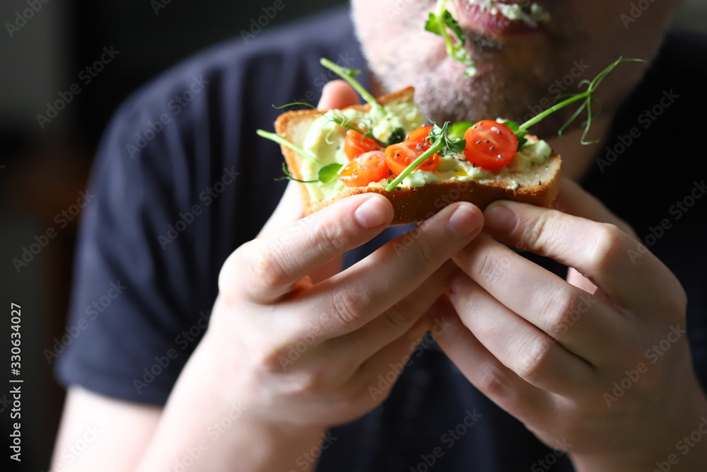 Toasts with microgreens. Hand holds a healthy toast. A man eats a diet toast with microgreens. Healthy food concept. Super food. Toasts with microgreens. Hand holds a healthy toast. A man eats a diet toast with microgreens. Healthy food concept. Super food.