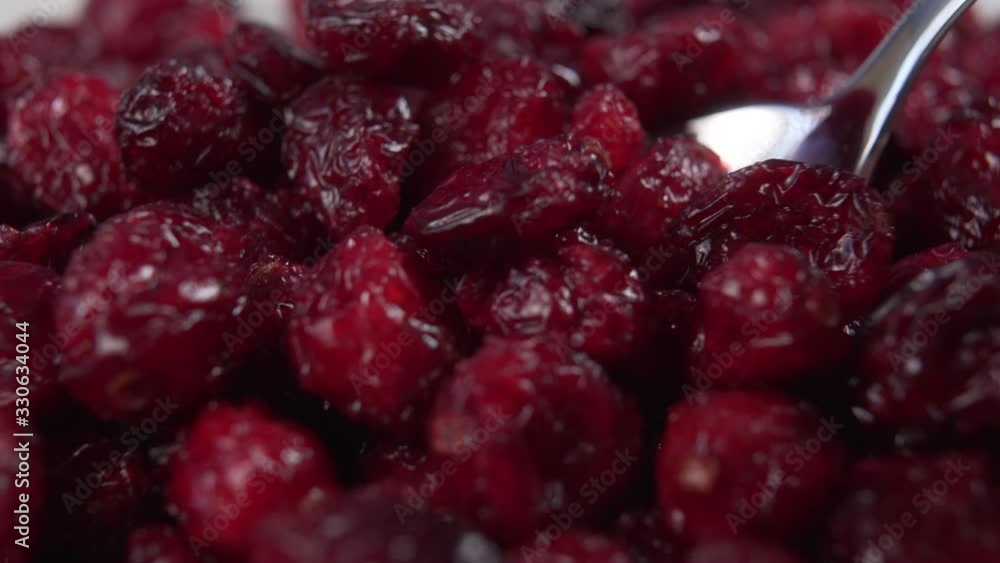 Spoon picks up berries of red dried cranberries close-up. Macro shot. Spoon picks up berries of red dried cranberries close-up. Macro shot.