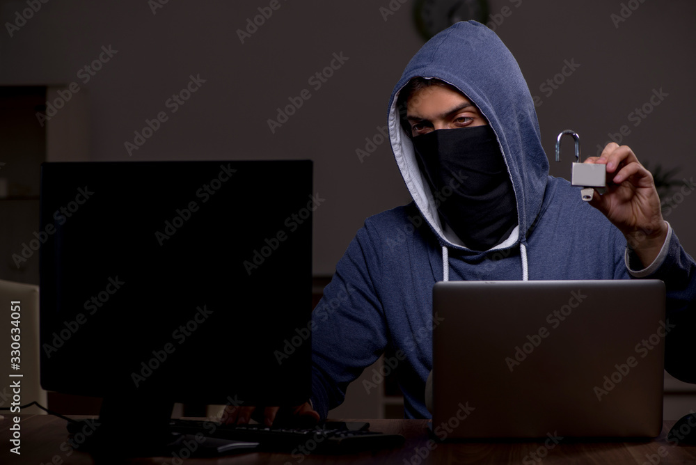 Male hacker hacking security firewall late in office Male hacker hacking security firewall late in office