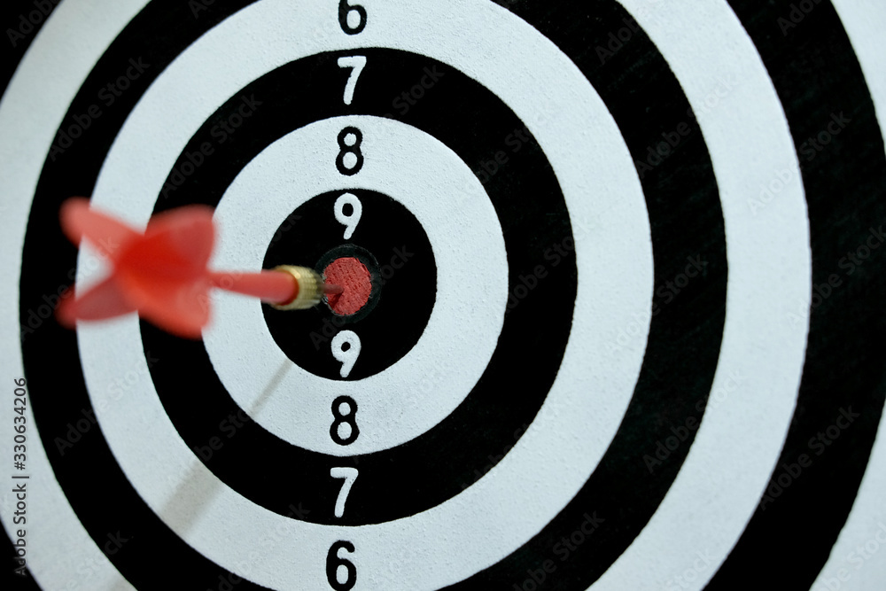 Conceptual photo of business strategy / accuracy - a red arrow that sticks directly in the center of the target dartboard Conceptual photo of business strategy / accuracy - a red arrow that sticks directly in the center of the target dartboard