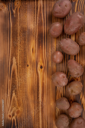 Fresh potatoes arranged on a wooden table top background to form a page border. Bio food