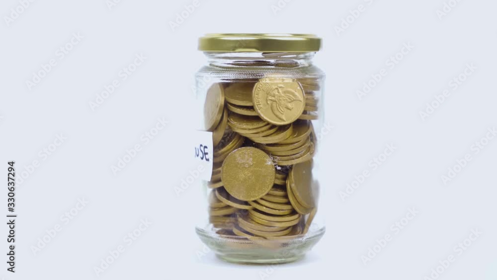 Glass jar with gold coins for house on the table Glass jar with gold coins for house on the table