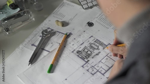 Architect's desk: drawings, tape measure and other drawing tools. Engineer works with drawings in a office, close-up. Insturments and office for designer. Male hands draw with a pencil. photo