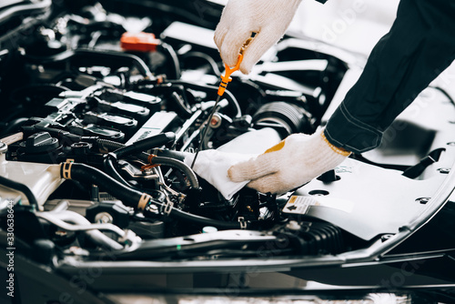 Check engine oil level Close up hands checking lube oil level of car engine from deep-stick for service and maintenance concept. © somchai20162516