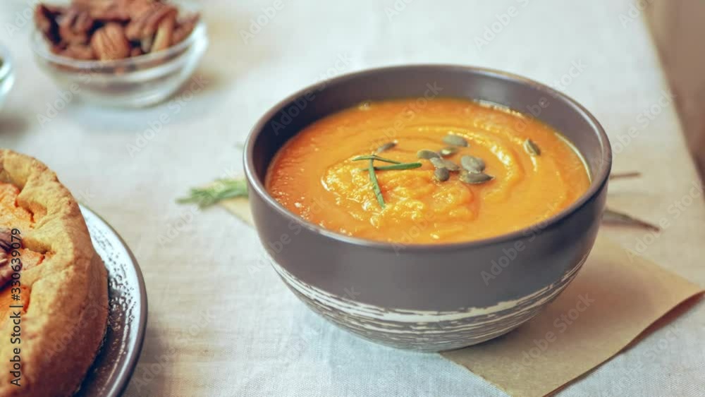 Dining table in the hands of a girl serves pumpkin soup. organic healthy foods are served Dining table in the hands of a girl serves pumpkin soup. organic healthy foods are served