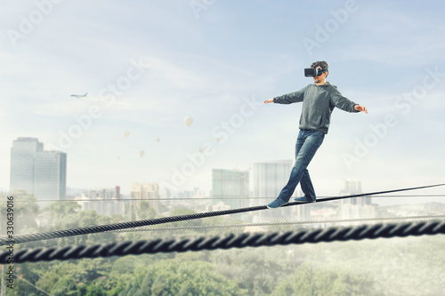 Man wearing virtual reality goggles and balancing on rope