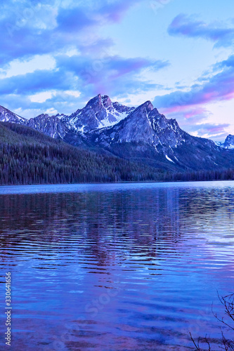 Purple mountain majesty jutting out of blue glacial lake with blue and purple sky