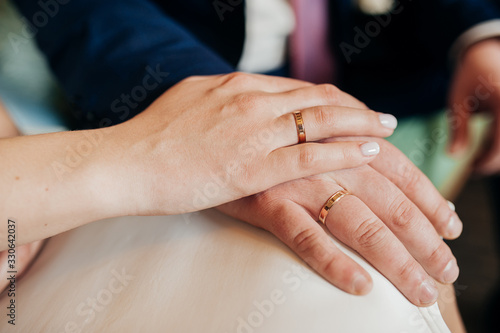 Hands newlyweds close-up with identical gold rings on the fingers, no faces.