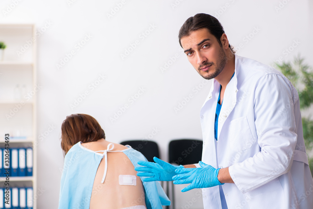 Fototapeta premium Injured young woman visiting young male doctor