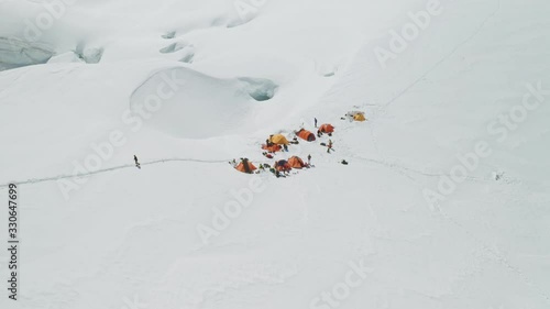 Alpinists camp on white wide snow mountain slope, highland mountaineers base