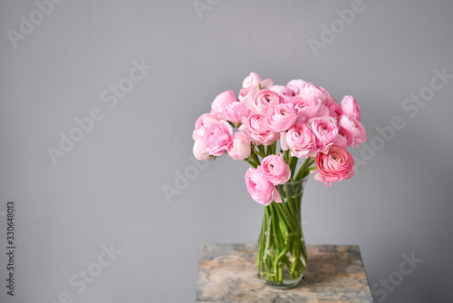 Wallpaper Mural Spring background, flower Wallpaper. Persian buttercup. Bunch pink ranunculus flowers on light gray background. Vase on vintage wooden table. Wallpaper Torontodigital.ca