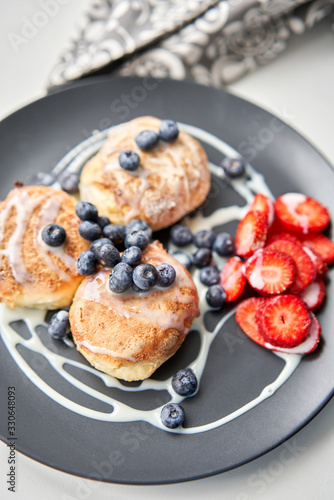 Wallpaper Mural Cottage cheese pancakes or syrniki with blueberry and strawberries on black plate, closeup view. Condensed milk sauce. Russian, Ukrainian cuisine. Healthy tasty breakfast Torontodigital.ca