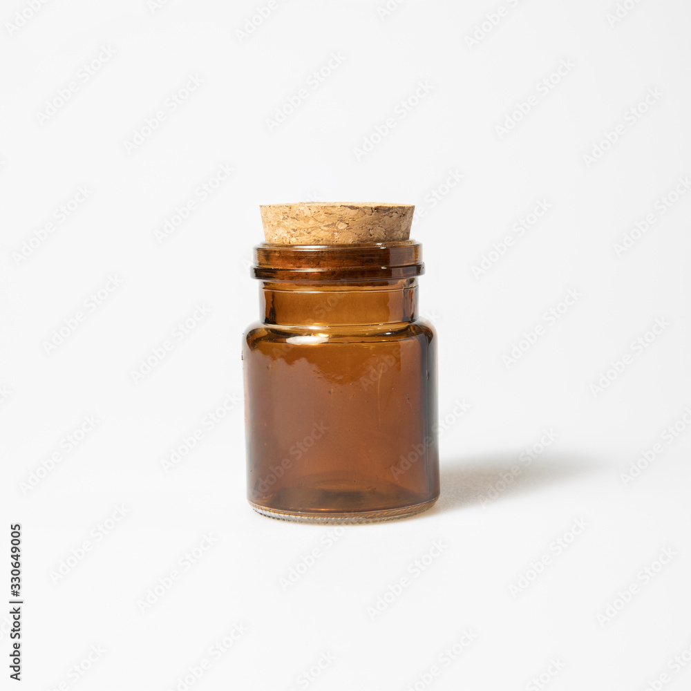 front view of transparent empty brown glass jar bottle with closed cork cap lids on white background