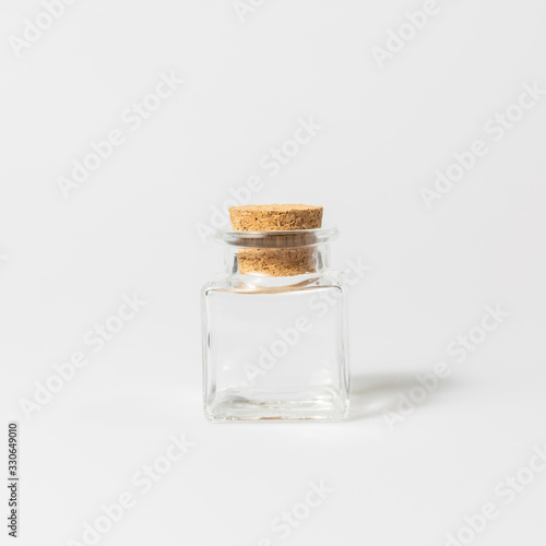 front view of transparent empty glass jar bottle with closed brown cork cap lids on white background