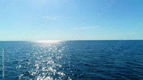 flying over calm ocean on sunny day with the clear sky photo