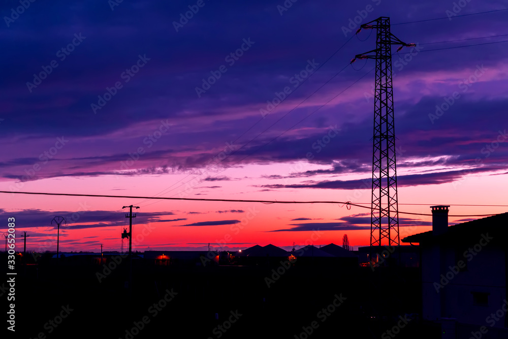 Fototapeta premium Traliccio elettrico al tramonto su paese di campagna.