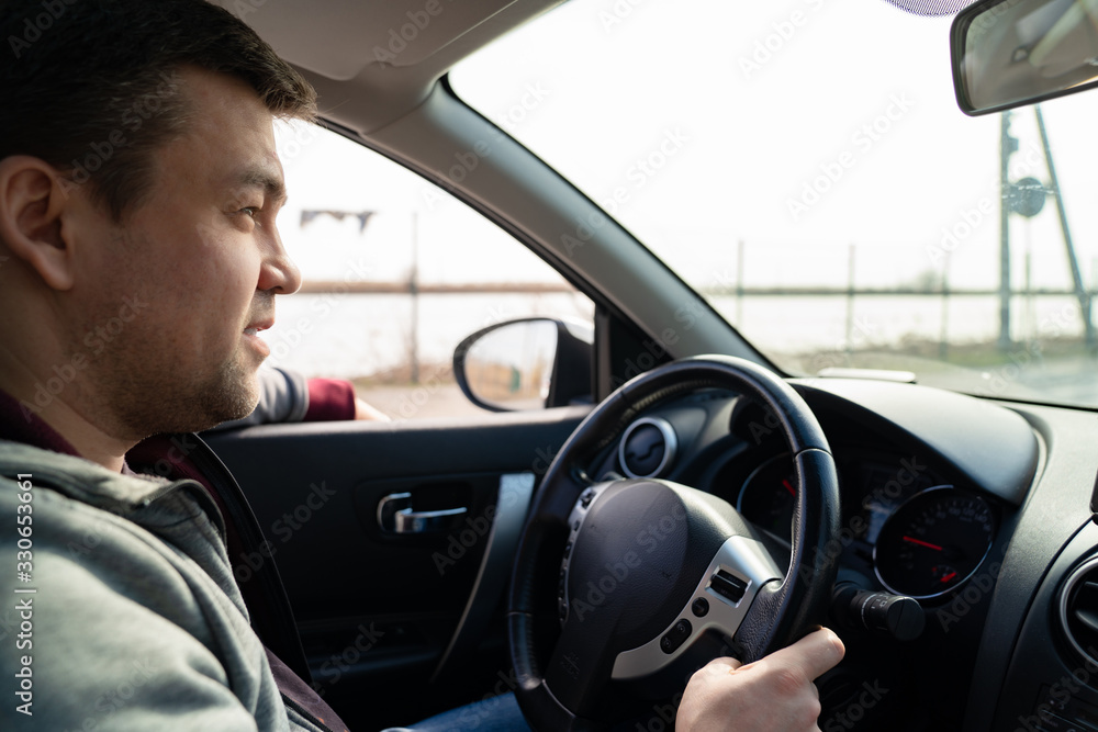 man in grey sweater behind wheel of car rides