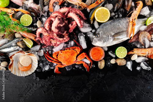 Fish and seafood variety, a flat lay top shot. Sea bream. shrimps, crab, sardines, mussels, octopus, scallops and caviar on ice with a place for text