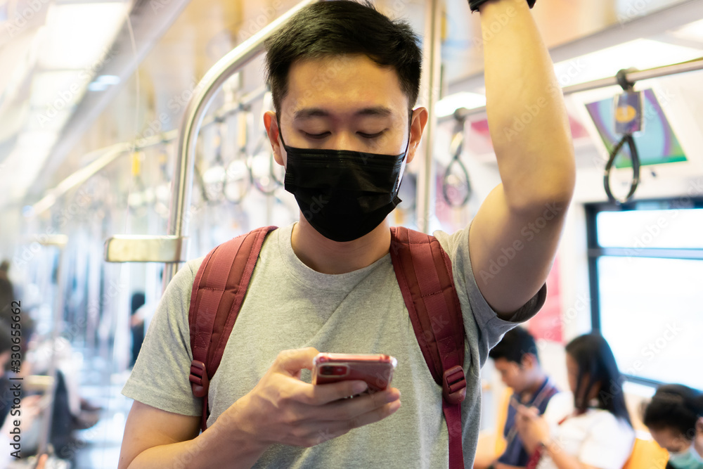 Close up of one young Asian man wearing black surgical face mask and using mobile  phone