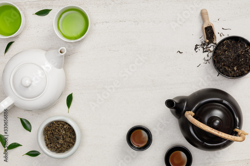 Tea cup with teapot, organic green tea leaves and dried herbs on the white stone desk empty space creative flat lay, Organic product from the nature for healthy with traditional style