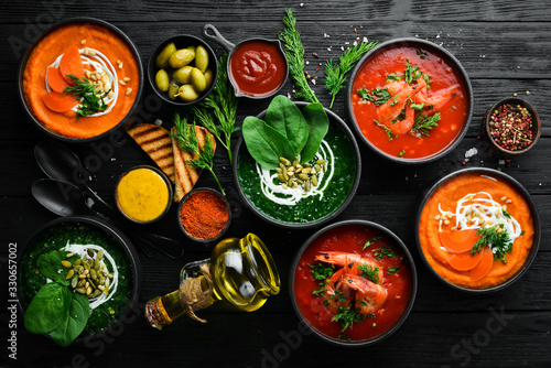 Set of colored soups. Spinach soup, tomato cream soup and carrot puree soup. Healthy food. On a black stone background.