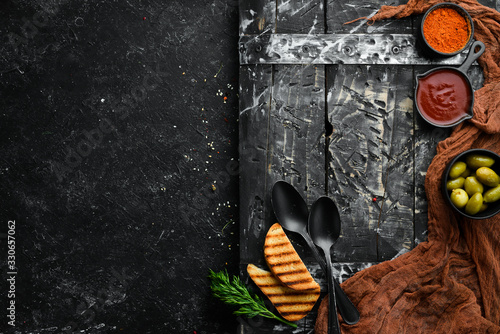 The background of cooking. A set of spices and fresh vegetables. Top view. Free space for your text. On a black stone background.