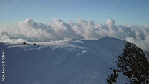 Mountain top achieved, alpinists on snow white summit above dense clouds