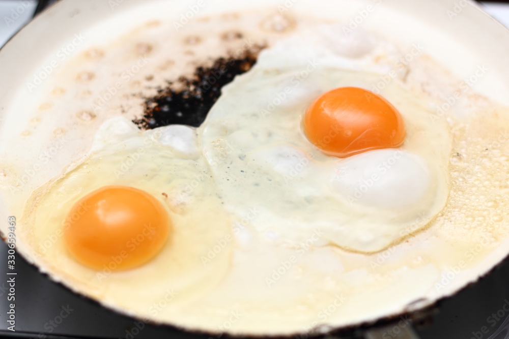 Frying eggs. Making sunny side up eggs with black pepper and salt. Frying eggs. Making sunny side up eggs with black pepper and salt.