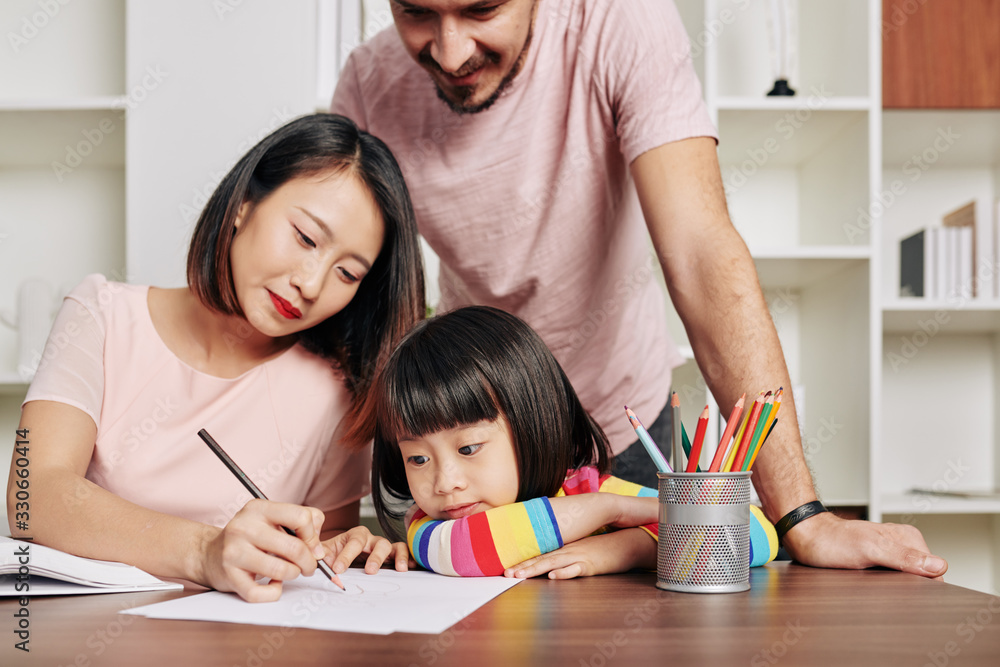 Parents explaining daughter difficult topic and drawing something on white sheet Parents explaining daughter difficult topic and drawing something on white sheet