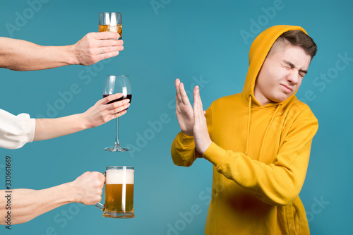Leinwand Poster Teenager in a yellow sweatshirt refuses different types of alcohol