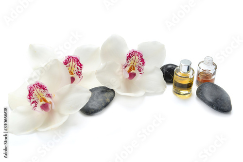 Photo oil bottles and pebbles with beautiful orchids on white background