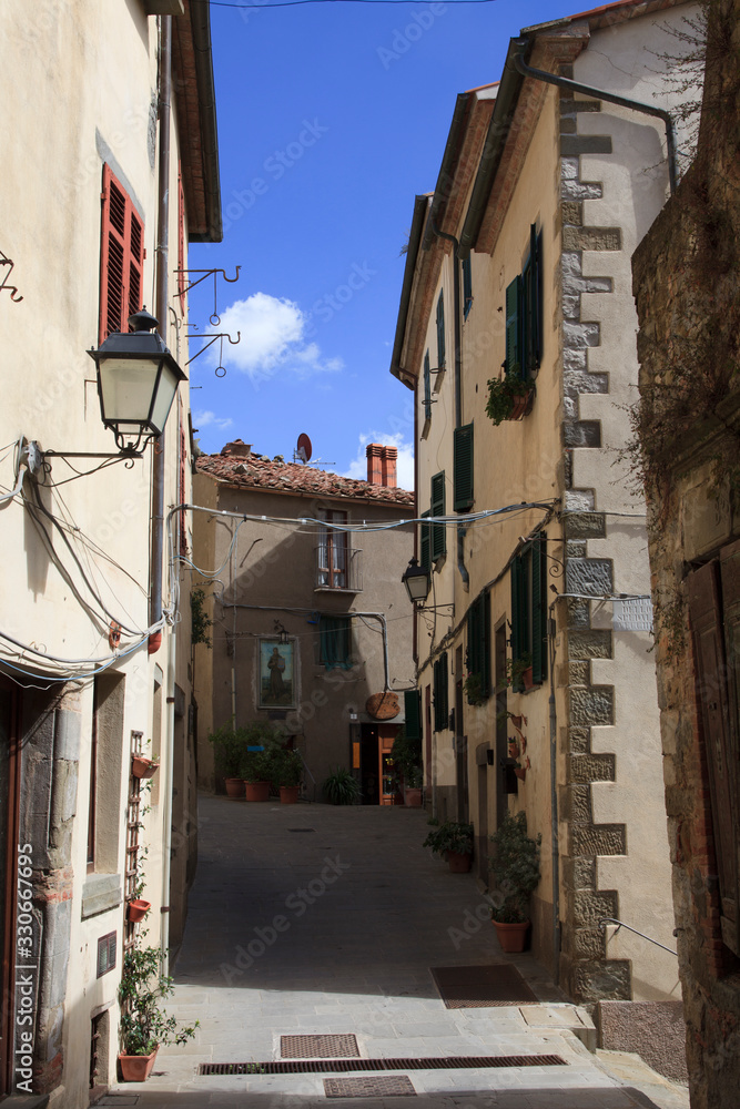 Fototapeta premium Scansano (GR), Italy - June 10, 2017: A central road and typical houses in Scansano, Grosseto, Tuscany, Italy