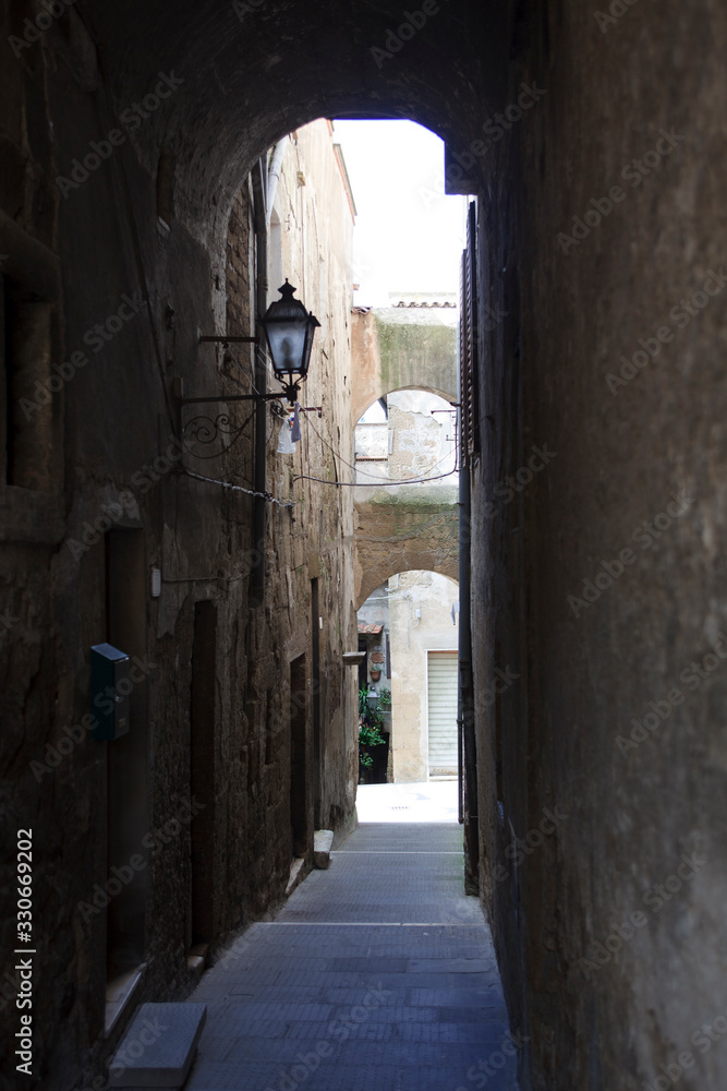 Pitigliano (GR), Italy - June 12, 2017: A central road and typical houses in the historic hilltop in Pitigliano village, Grosseto, Tuscany, Italy Pitigliano (GR), Italy - June 12, 2017: A central road and typical houses in the historic hilltop in Pitigliano village, Grosseto, Tuscany, Italy