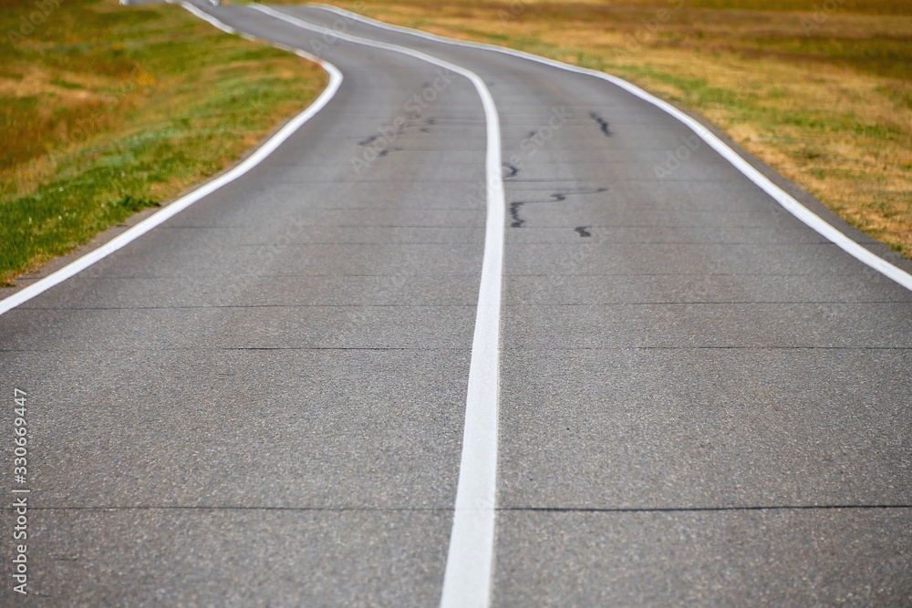 Road in a field on a summer day. Asphalt road for cars in the field. Road in a field on a summer day. Asphalt road for cars in the field.