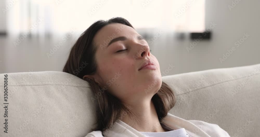 Relaxed young adult woman napping leaning asleep on comfortable couch at home. Serene beautiful lady resting on cozy sofa with eyes closed. Lazy tired girl enjoying peaceful sleep. Close up view Relaxed young adult woman napping leaning asleep on comfortable couch at home. Serene beautiful lady resting on cozy sofa with eyes closed. Lazy tired girl enjoying peaceful sleep. Close up view