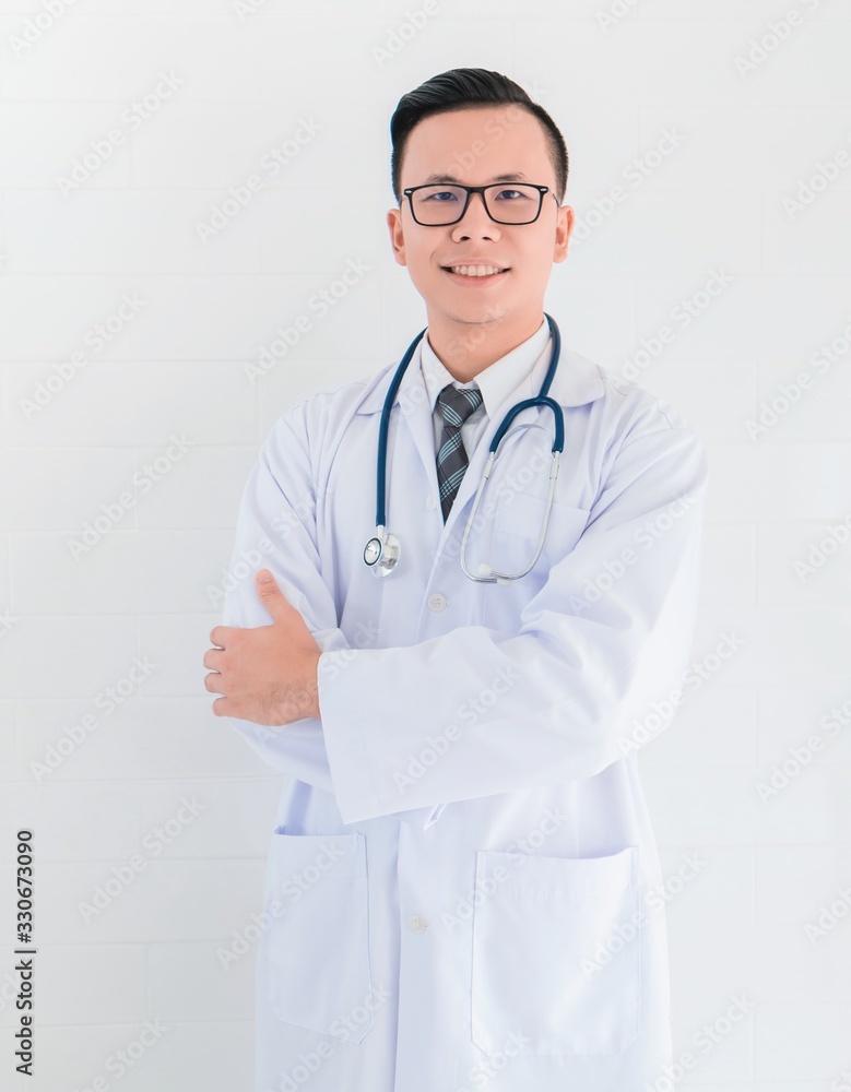 Portrait of smiling Asian medical male Doctor standing on white wall background.Concept of effective work in hospitals. Portrait of smiling Asian medical male Doctor standing on white wall background.Concept of effective work in hospitals.