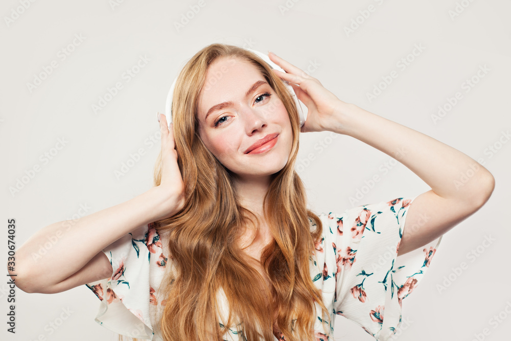 Obraz premium Young happy woman with headphones. Redhead model girl listening music on white