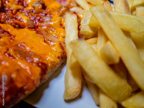  Close up of cheese and tomato pizza and oven chips on a dinner plate with selective focus on part of the pizza