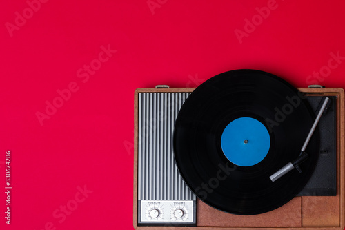 Vintage vinyl player and turnable on a red background. Entertainment 70s. Listen to music. Top view. photo