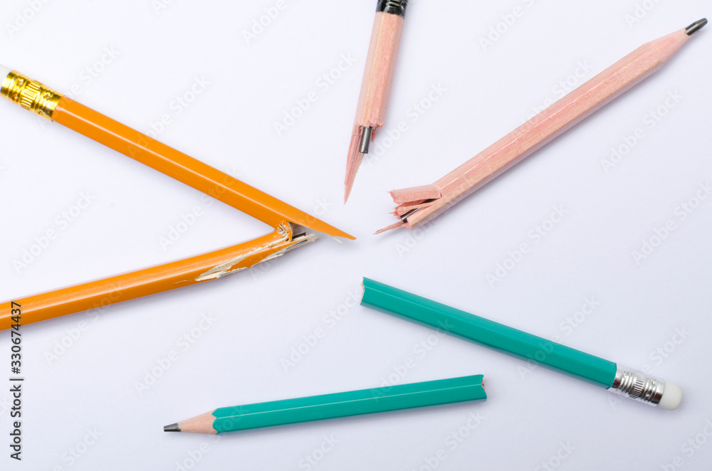 Top view of broken several pencils on the white paper.Concept of hard learning and stress Top view of broken several pencils on the white paper.Concept of hard learning and stress