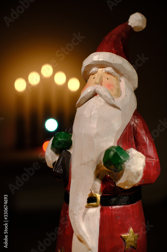 santa claus decoration in front of candle lights with room for copy