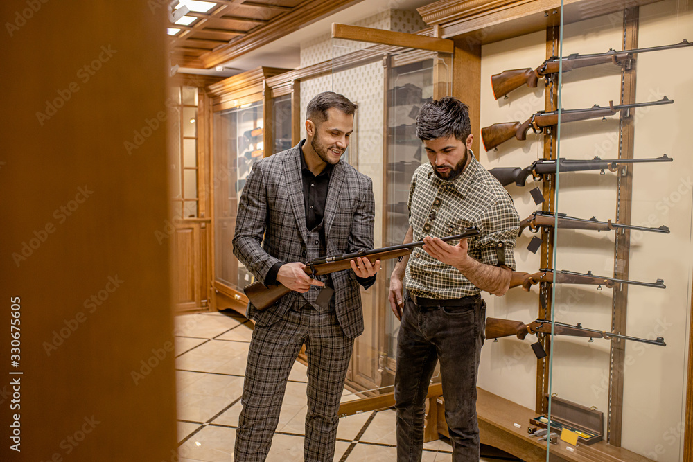 confident and affable salesman, consultant give good rifle, gun for hunting to look. customer want to make purchase in guns store, he is keen on hunting