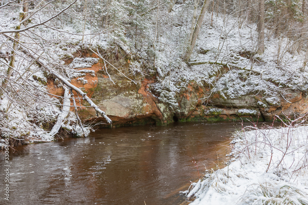 City Ligatne, Latvia. River in winter with sandstone cliffs and caves.