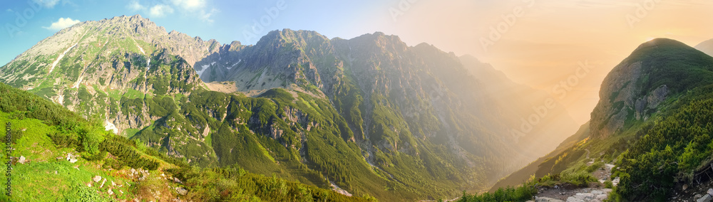 Wide panorama of deep mountain gorge in morning sunlight