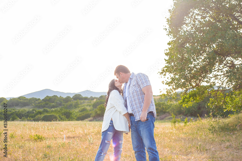 Pregnant woman and husbant kiss on the field. Happy people love spending time together in the nature Pregnant woman and husbant kiss on the field. Happy people love spending time together in the nature