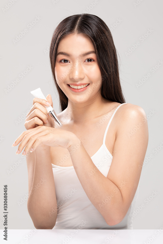 Beautiful Young Asian Woman Holding luxury white clean tube smile feeling so happy and cheerful with healthy Clean and Fresh skin,isolated on gray background,Beauty Cosmetics Concept Beautiful Young Asian Woman Holding luxury white clean tube smile feeling so happy and cheerful with healthy Clean and Fresh skin,isolated on gray background,Beauty Cosmetics Concept